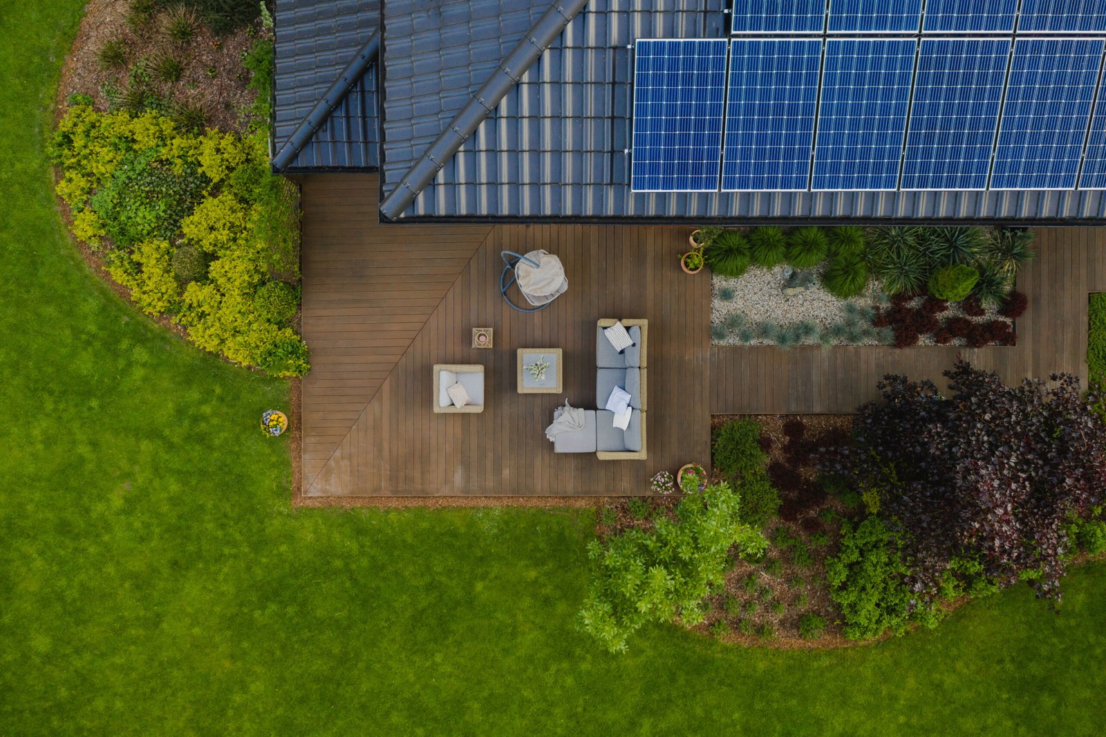 Top view of suburban house with green garden and wooden terrace